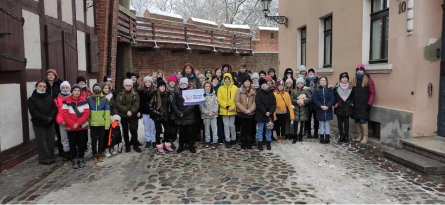 Grupa dzieci stoi między kamienicami w Toruniu
